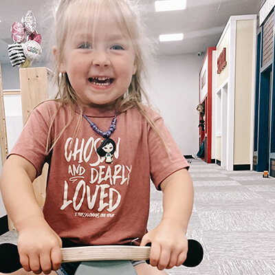 Girl riding on wooden tricycle